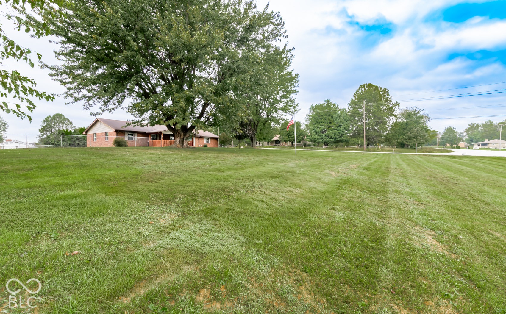 Expansive lawn featuring mature trees and a brick exterior dwelling