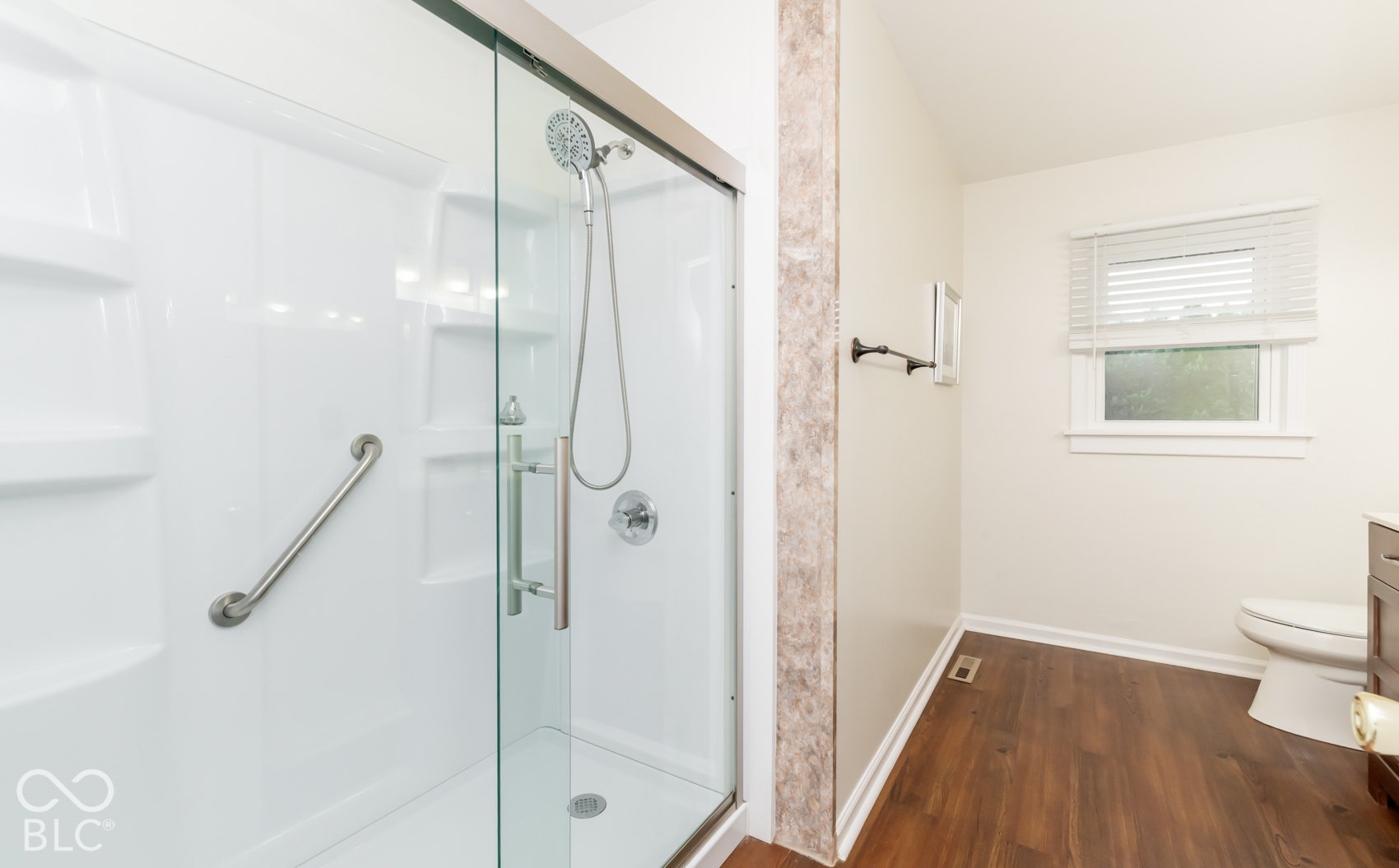 Enclosed shower with a sliding glass door, chrome fixtures, and a grab bar
