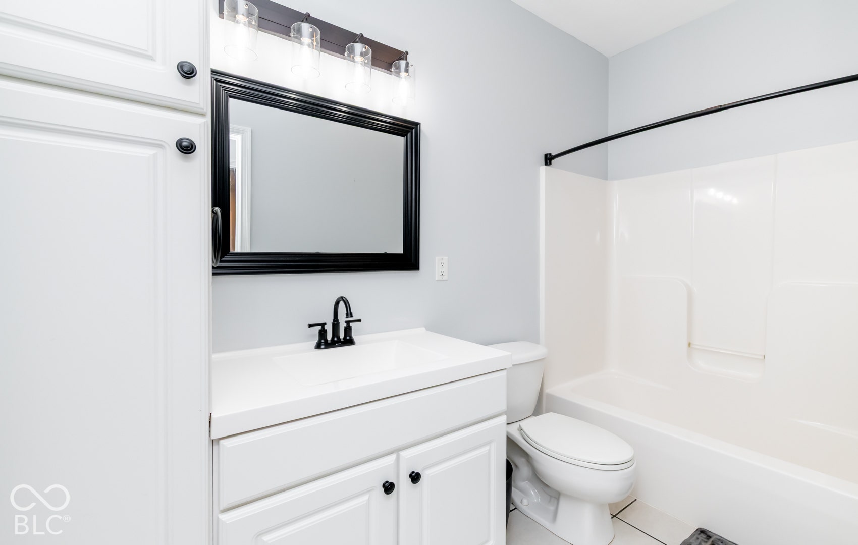 White vanity with integrated sink, matte black faucet, and framed mirror