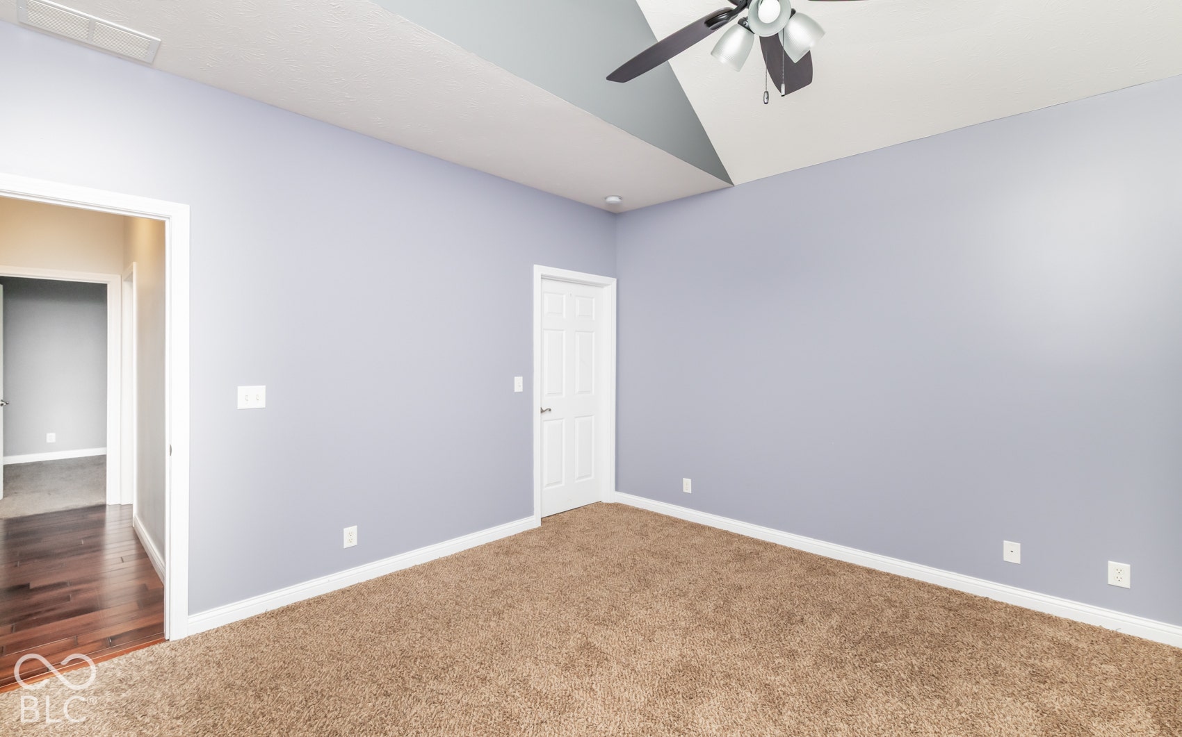 Carpeted room featuring a vaulted ceiling with a ceiling fan, light blue walls, and a white paneled door