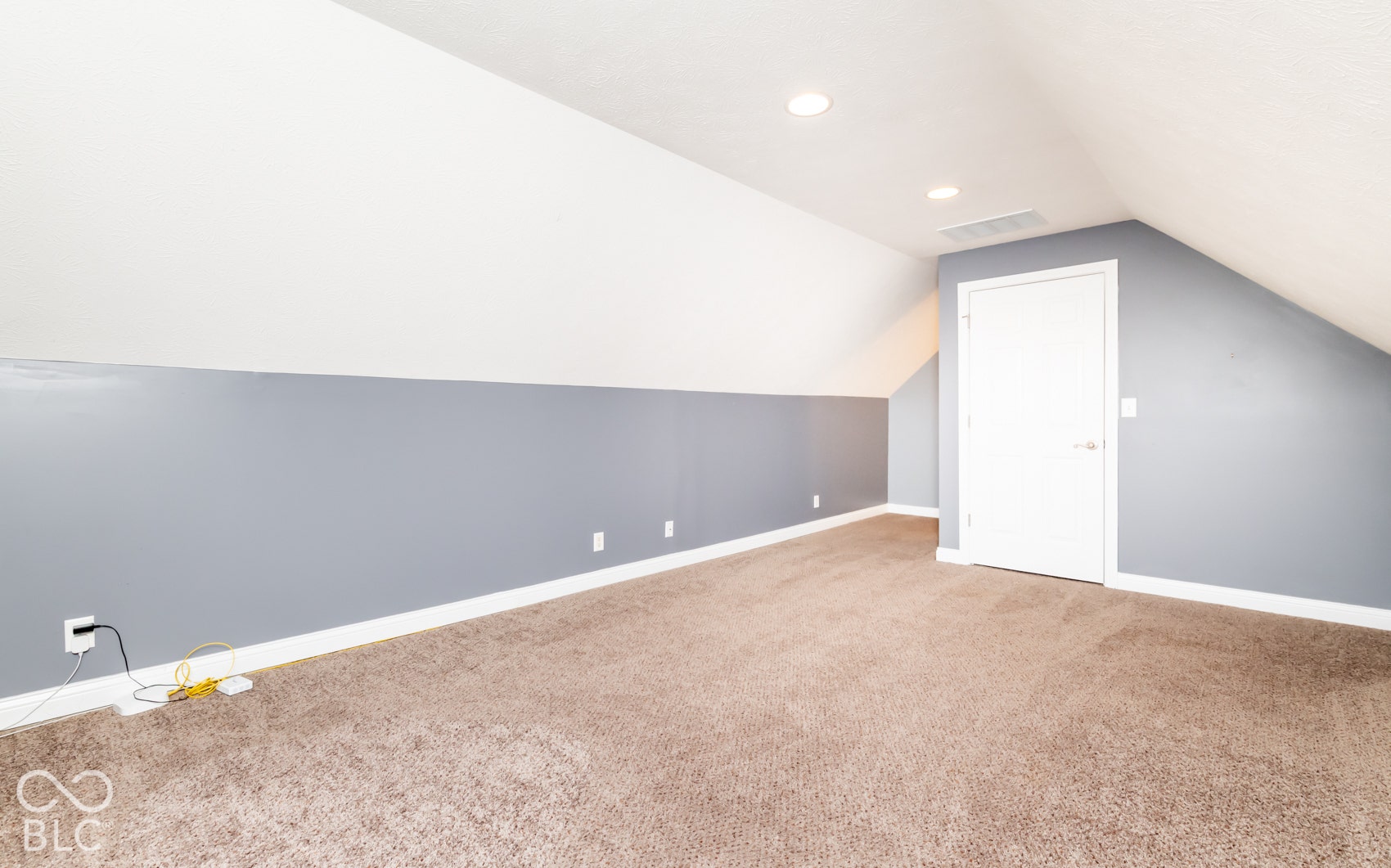 Sloped ceiling with recessed lighting, wall-to-wall carpeting, painted walls, and a white interior door