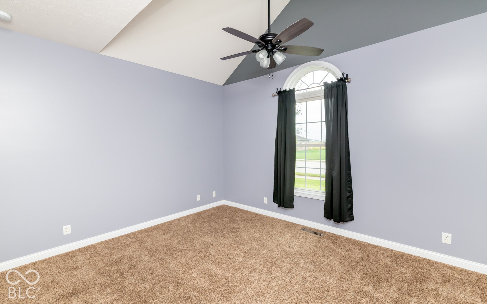 Vaulted ceiling, ceiling fan, arched window, wall-to-wall carpeting, and light-toned walls