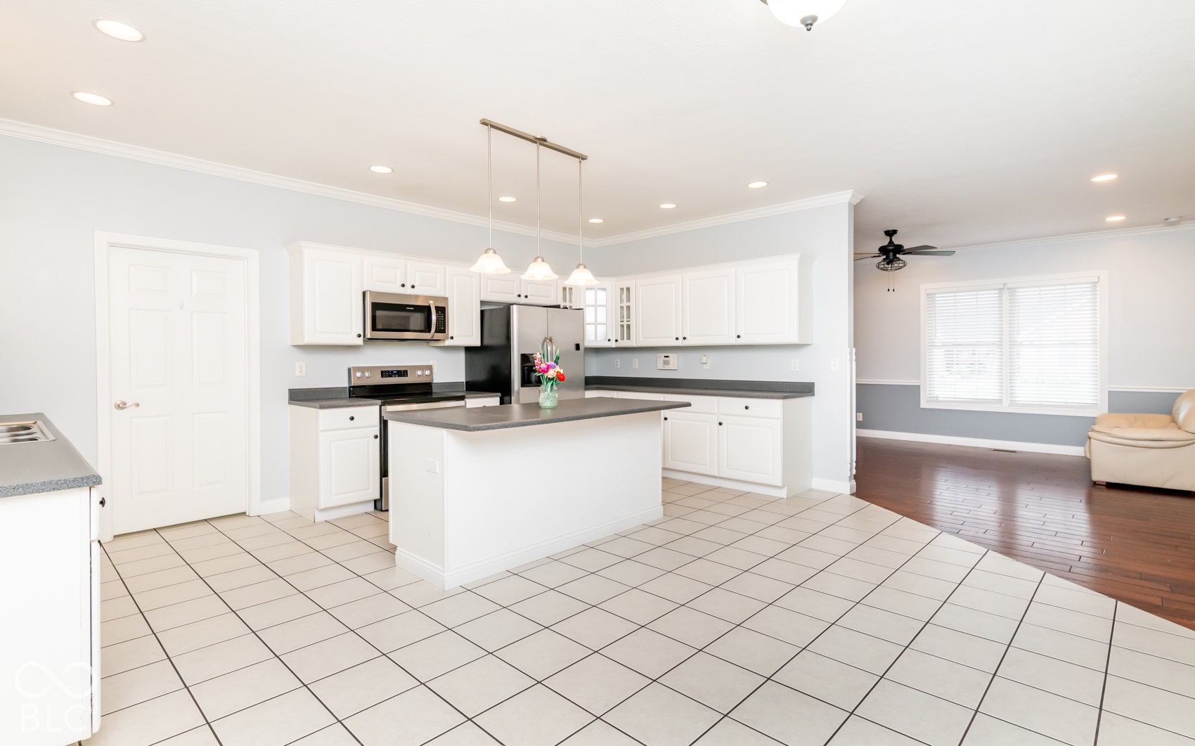 Kitchen featuring white cabinetry, stainless steel appliances, a center island with pendant lighting, and tile flooring