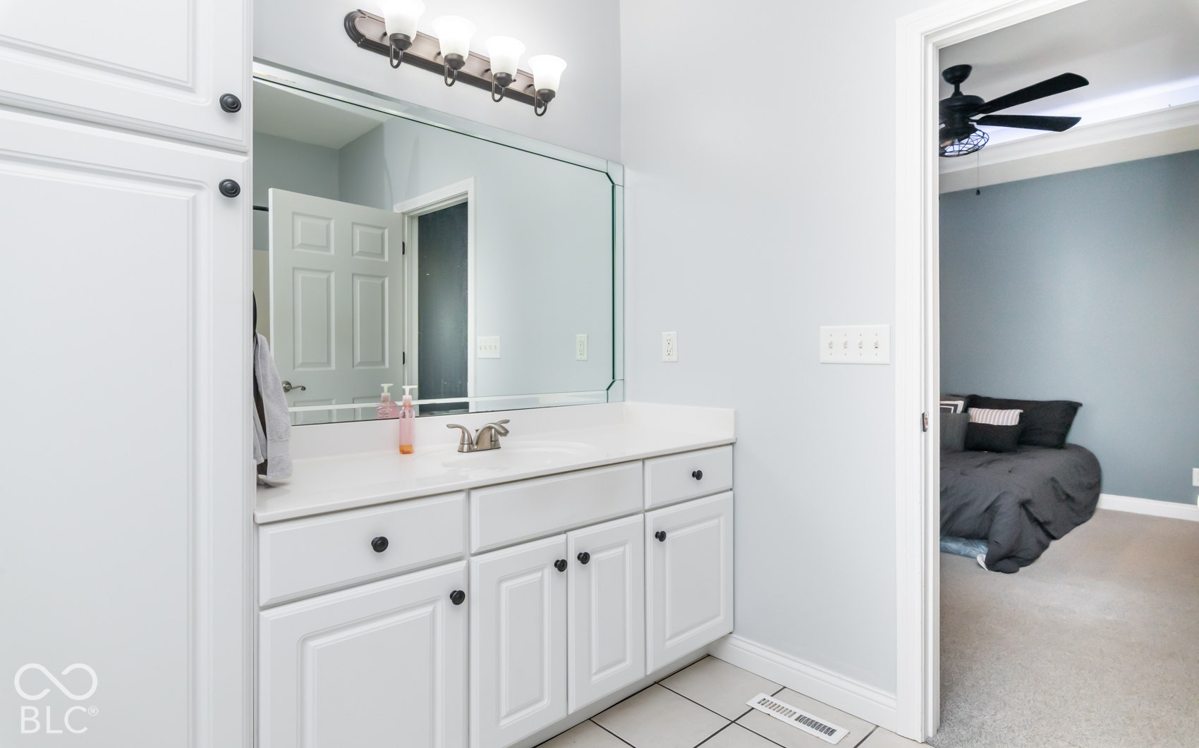 White cabinetry with black hardware, white countertop, and a vanity-width mirror