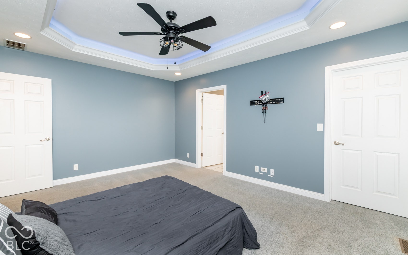 Tray ceiling with recessed lighting, crown molding, and a ceiling fan