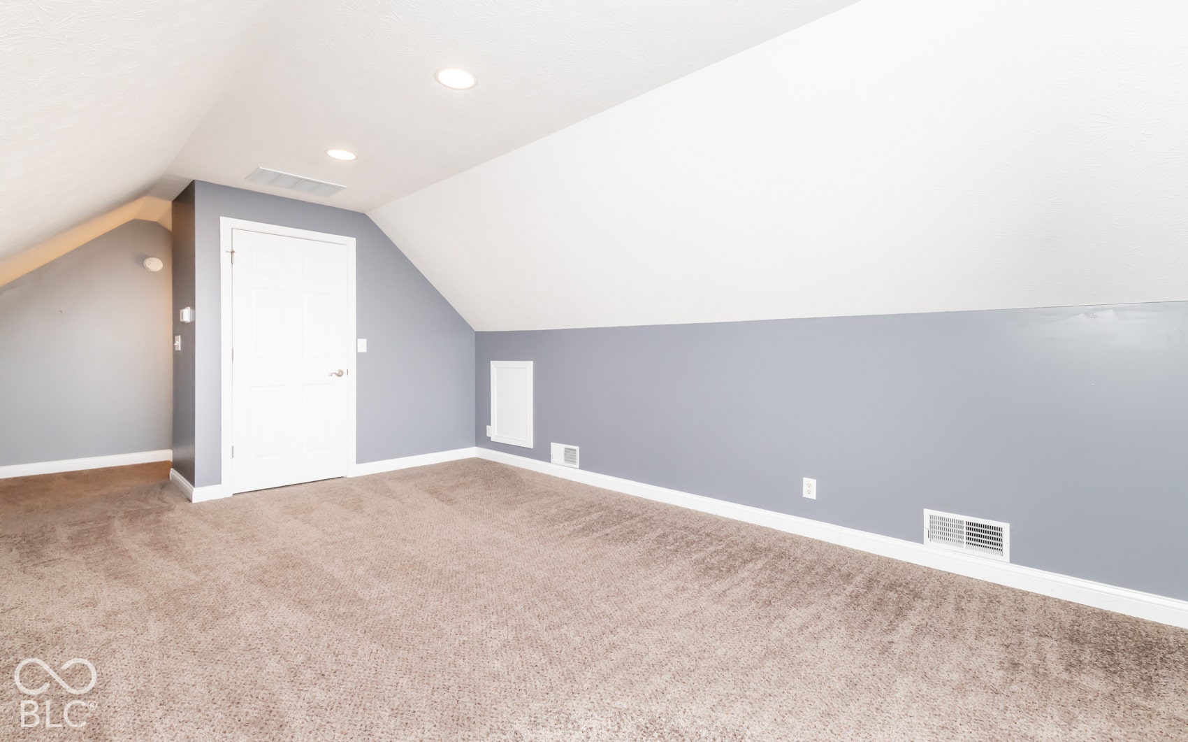 Sloped ceilings, recessed lighting, neutral carpeting, and a paneled interior door