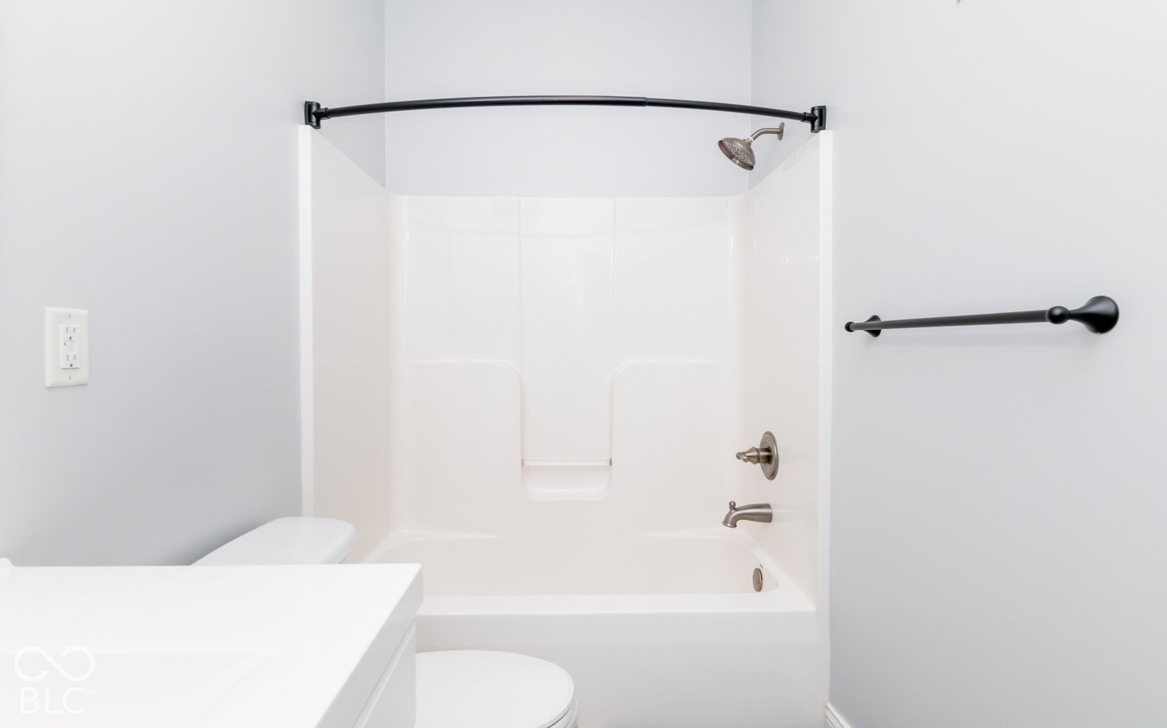 Tub/shower combination with a curved shower rod, brushed nickel fixtures, and a white surround