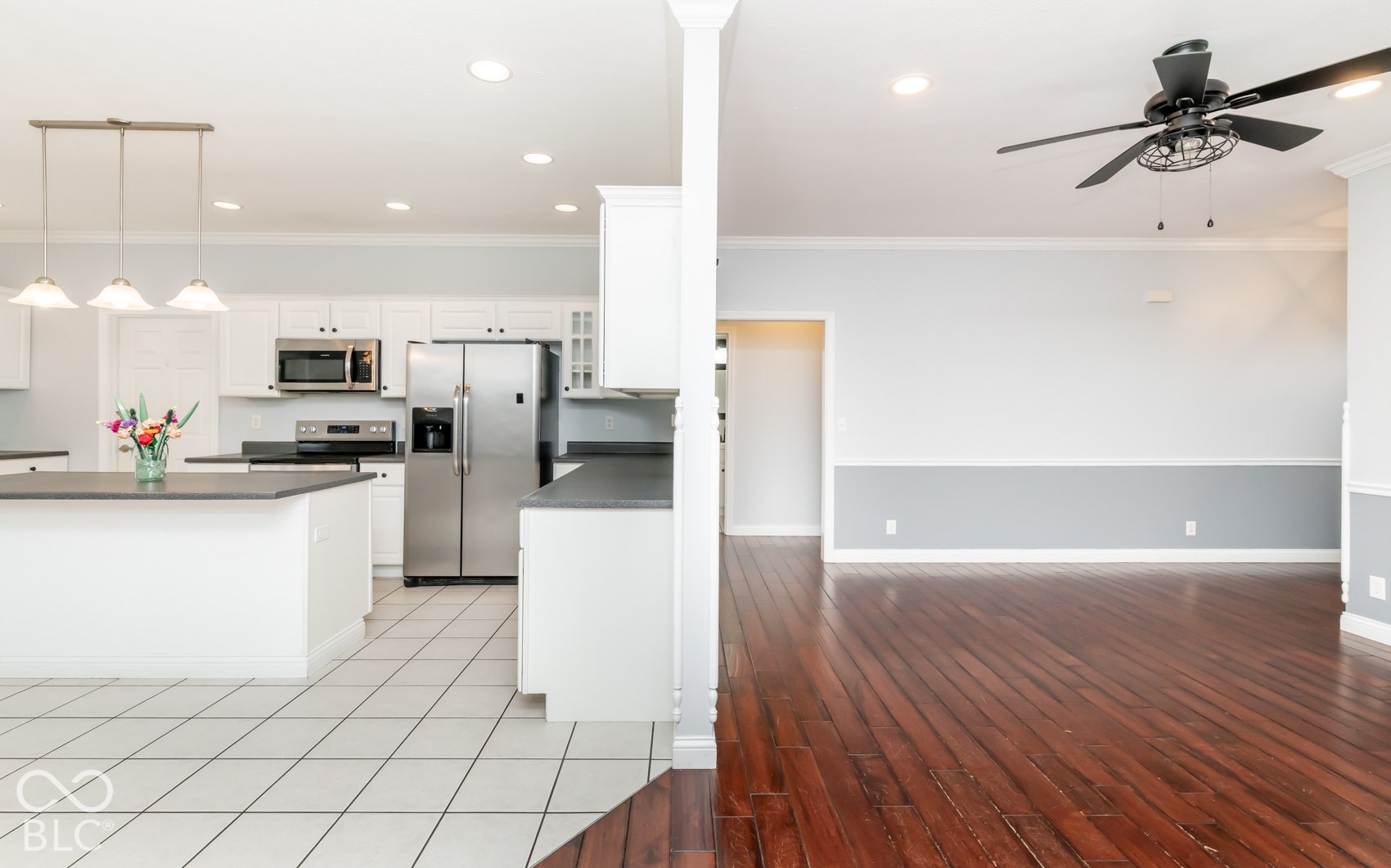 Kitchen featuring white cabinetry, stainless steel appliances, an island with pendant lighting, and tile flooring