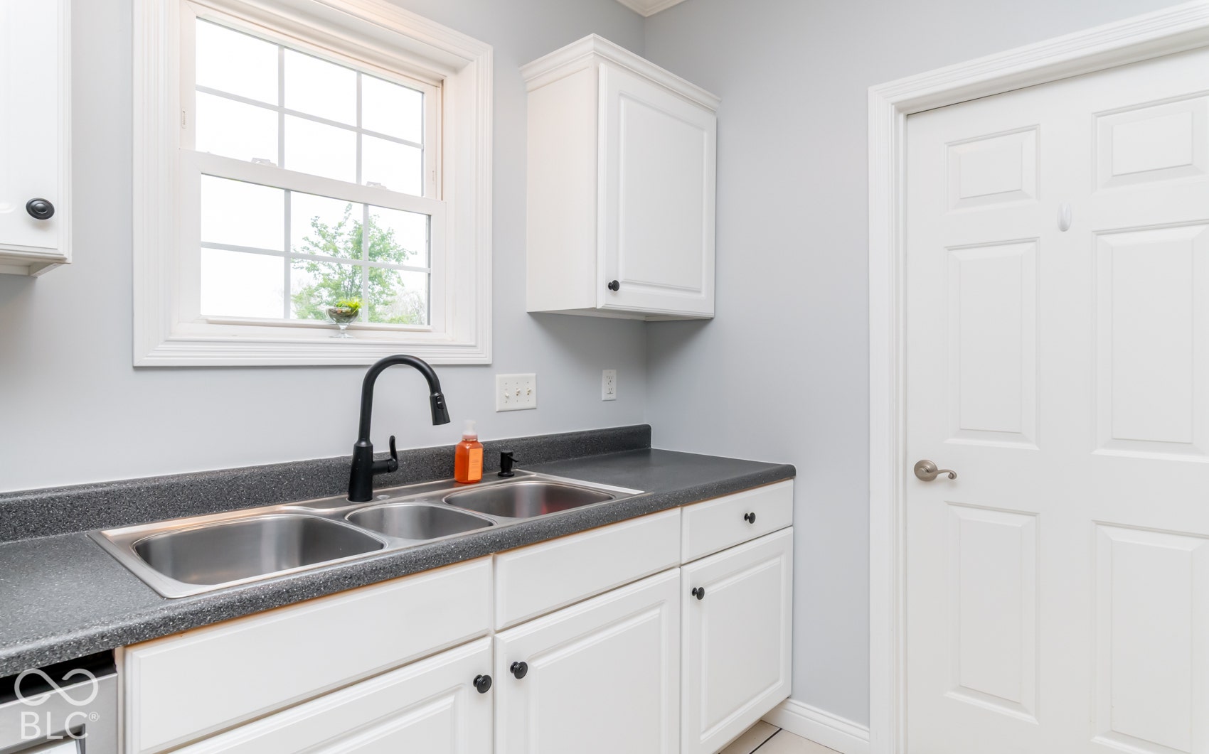 White shaker-style cabinetry with heart-shaped hardware, dual stainless steel basin sink, matte black gooseneck faucet, and gray countertop