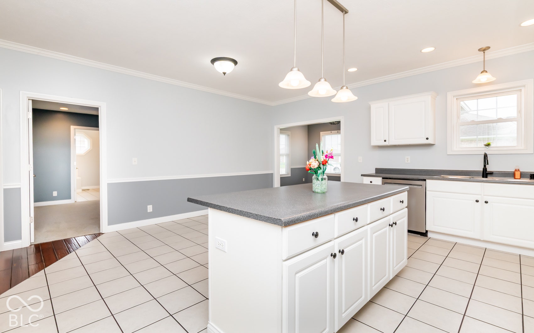 Kitchen featuring white cabinetry, a central island with integrated storage, stainless steel appliances, and tile flooring
