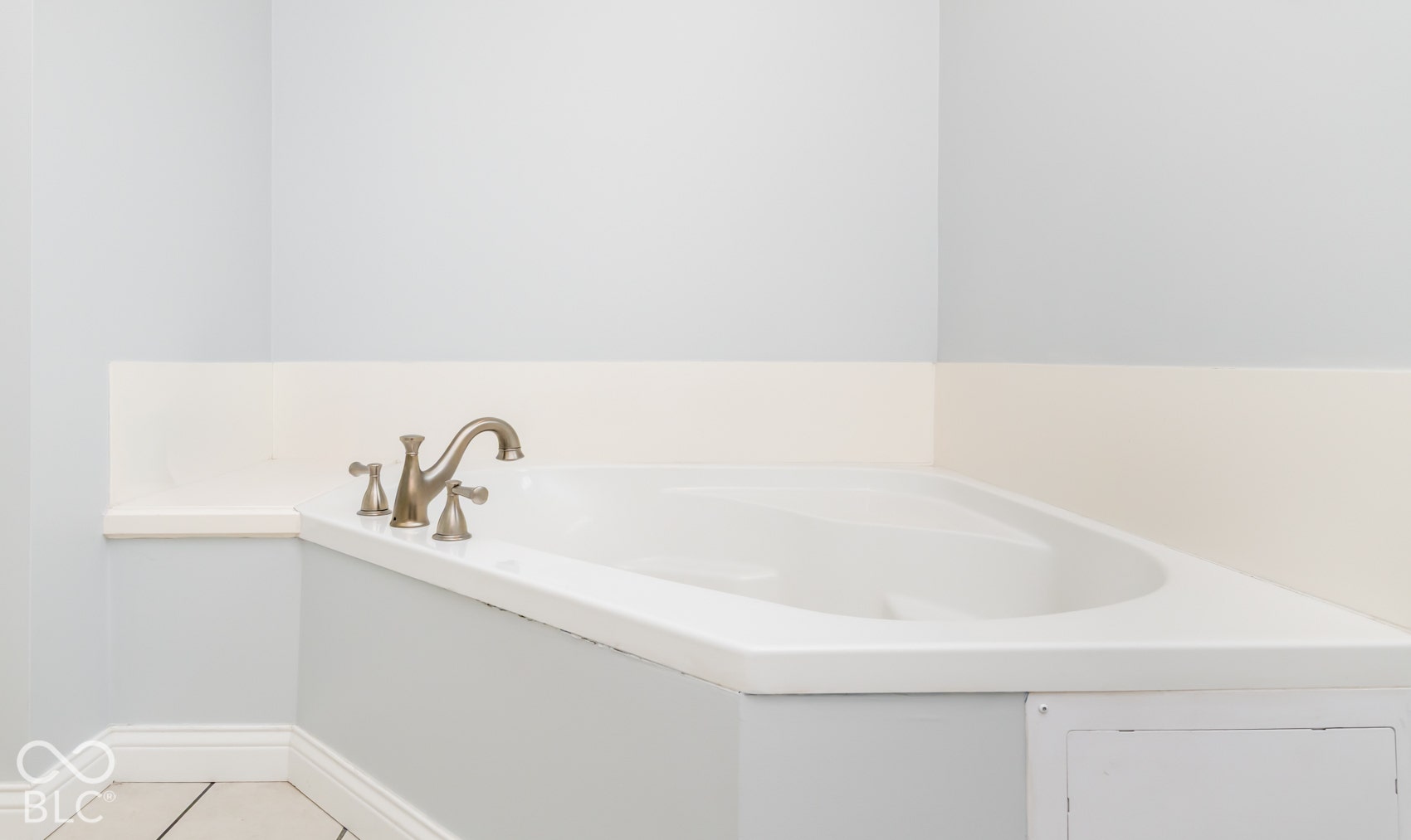 Corner soaking tub featuring brushed nickel fixtures and a tiled surround