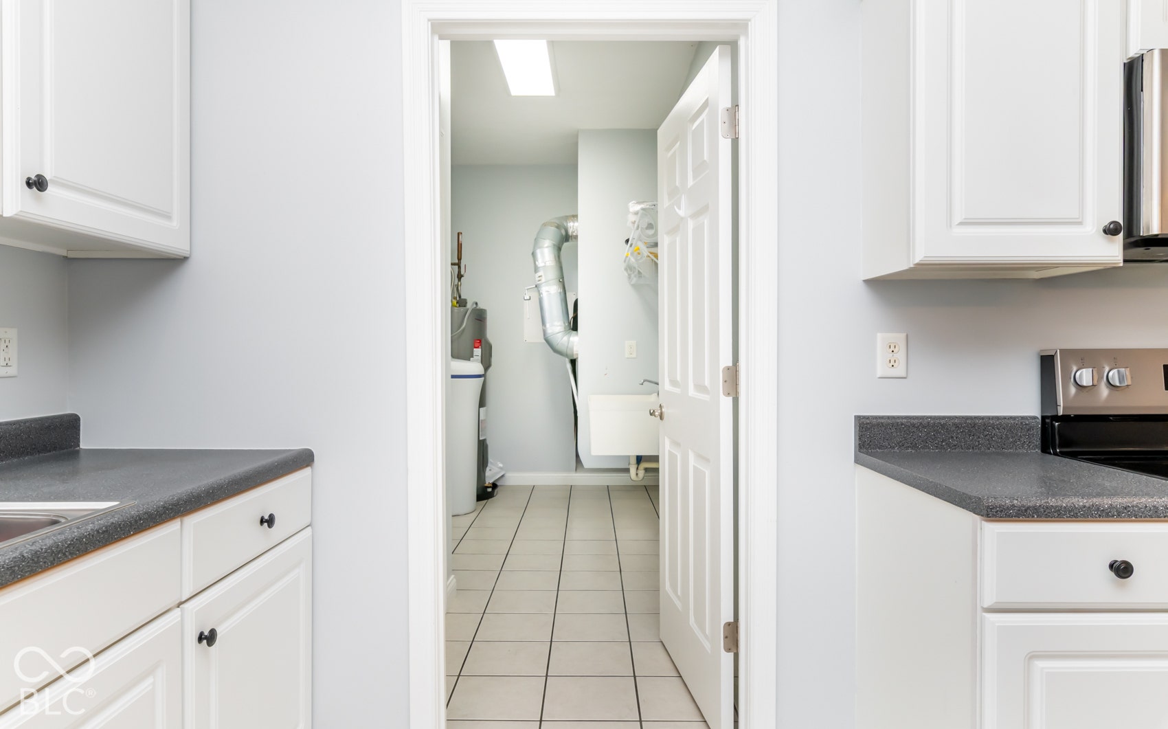 White shaker-style cabinetry with dark hardware, dark countertops, and tile flooring