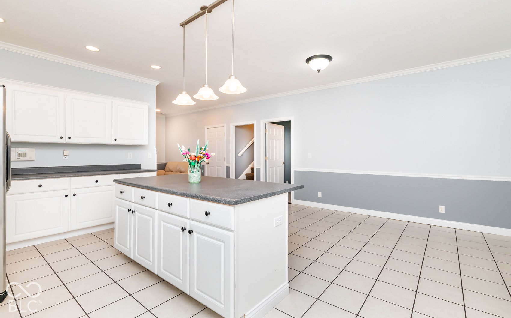 Kitchen featuring white cabinetry, a central island, dark countertops, and tile flooring