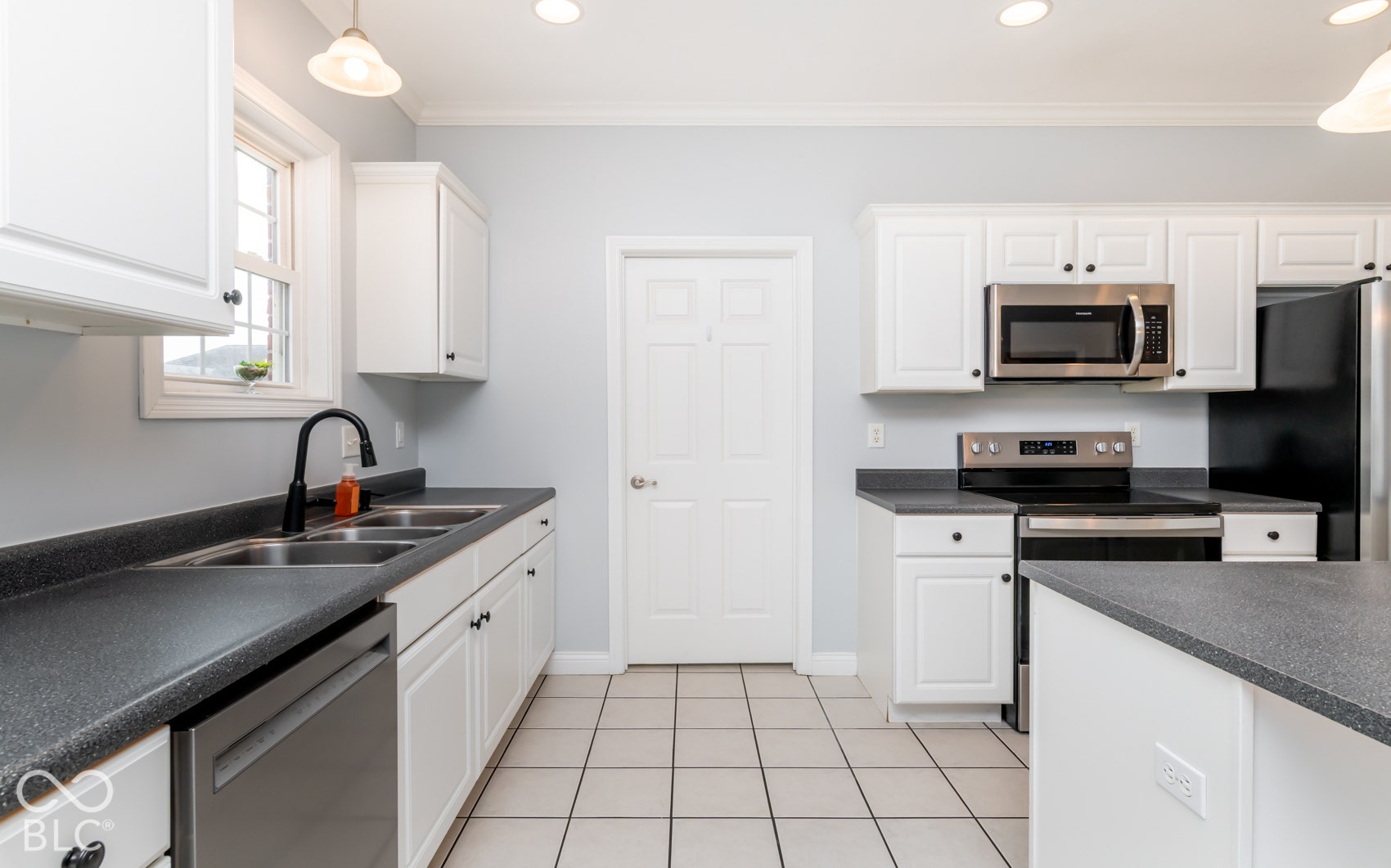 White cabinetry, stainless steel appliances, dual basin sink, window above sink, tile flooring