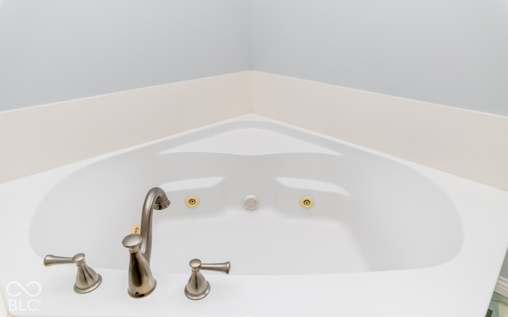 Built-in corner tub with brushed nickel fixtures and integrated jets