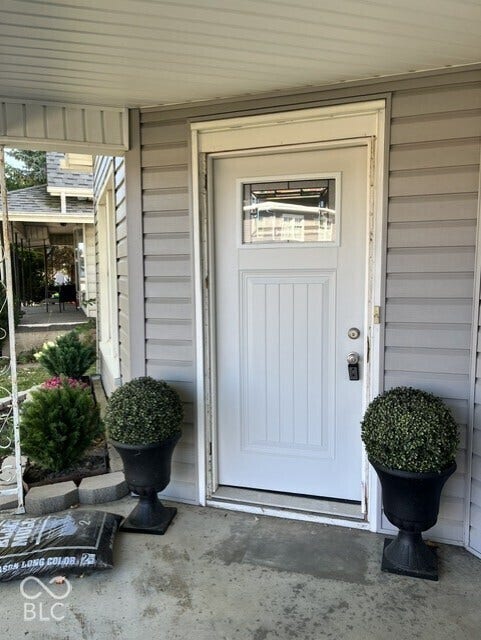 415 W Main, Greensburg, IN 47240 White paneled entry door with an upper window insert, gray siding, and a concrete porch