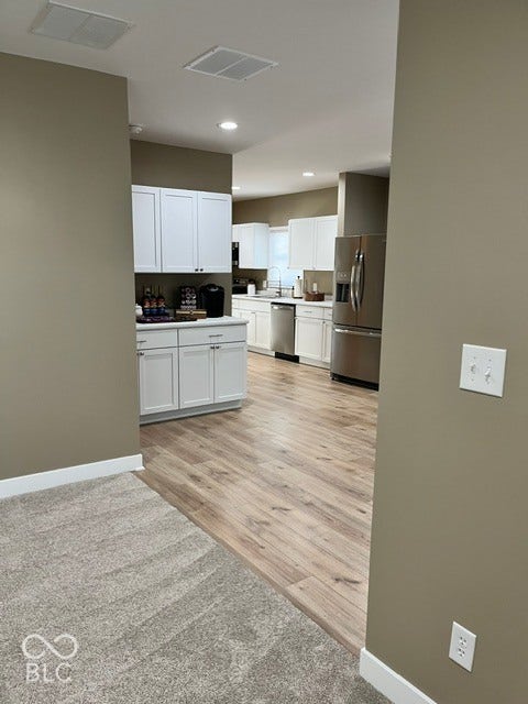 415 W Main, Greensburg, IN 47240 Living Room looking into Kitchen featuring white cabinetry, laminate wood-finish flooring, stainless steel appliances, and recessed lighting