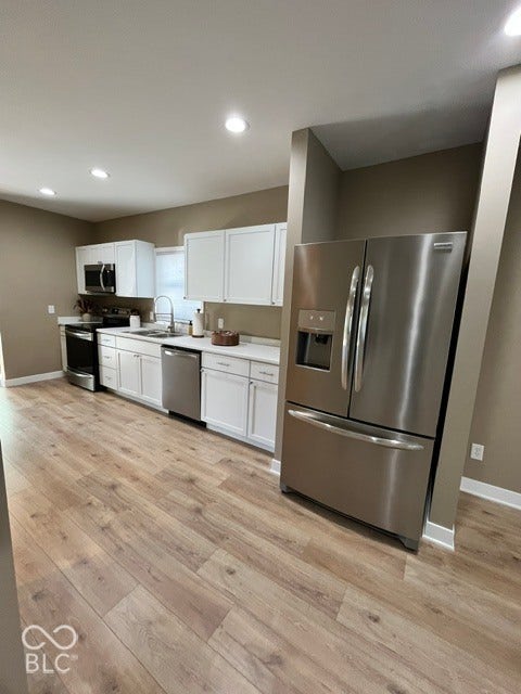415 W Main, Greensburg, IN 47240 Kitchen featuring stainless steel appliances, white cabinetry, laminate wood-finish flooring, recessed lighting, and light-toned countertops