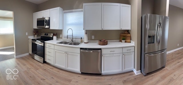415 W Main, Greensburg, IN 47240 Pano shot of the Kitchen featuring white cabinetry, stainless steel appliances, a double basin sink, light-toned laminate wood-finish flooring, and white countertops