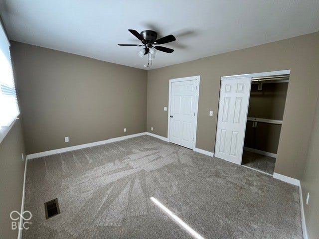 415 W Main, Greensburg, IN 47240 Carpeted room featuring a ceiling fan with lighting, a panel door, and a closet with a sliding panel door and built-in double layer shelving