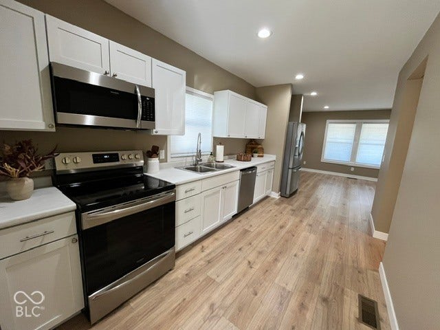 415 W Main, Greensburg, IN 47240 Kitchen featuring stainless steel appliances, white cabinetry, a double basin sink, and laminate wood-finish flooring