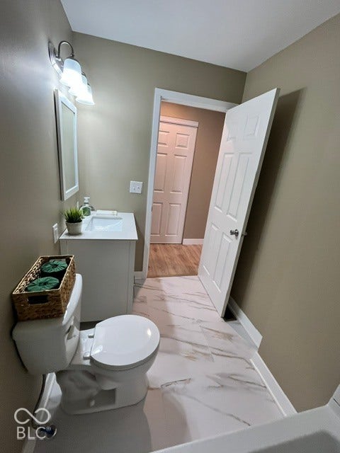415 W Main, Greensburg, IN 47240 Bathroom featuring a white vanity with an integrated sink, polished chrome light fixture, contemporary white toilet, and white flooring with veining