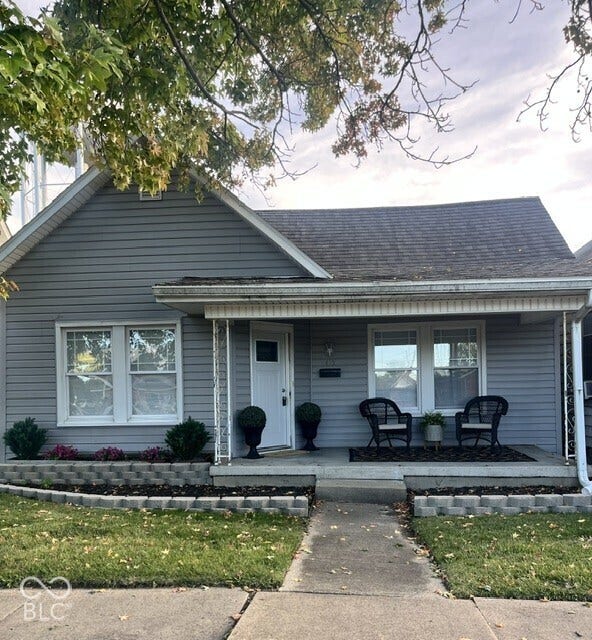 415 W Main, Greensburg, IN 47240 Gable roof structure with light gray siding exterior and a covered front porch, concrete walkway, and a landscaped front yard with decorative block retaining walls