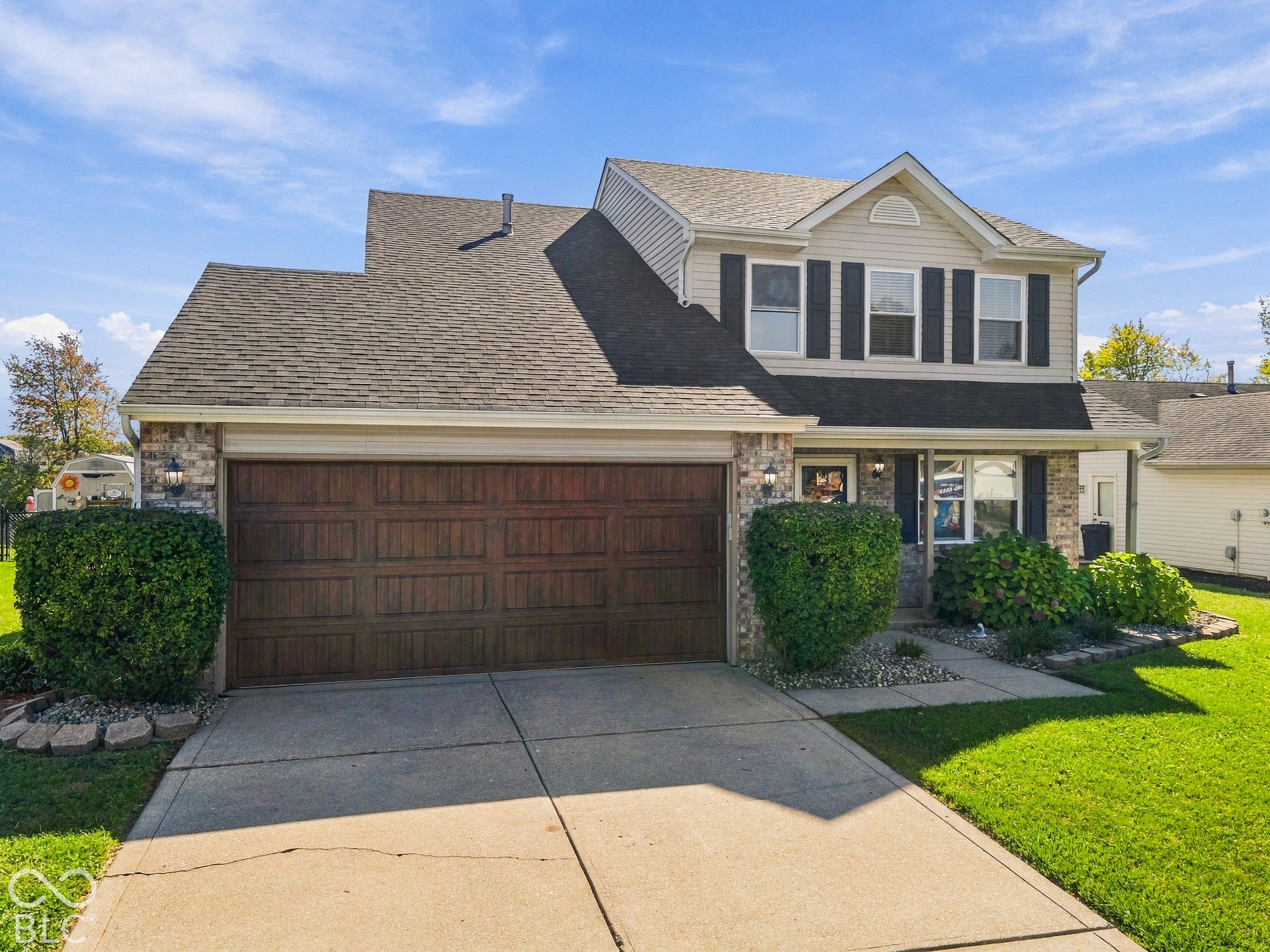 Two-story residence featuring a two-car garage with a wood-finish door, stone accents, and a gabled roofline