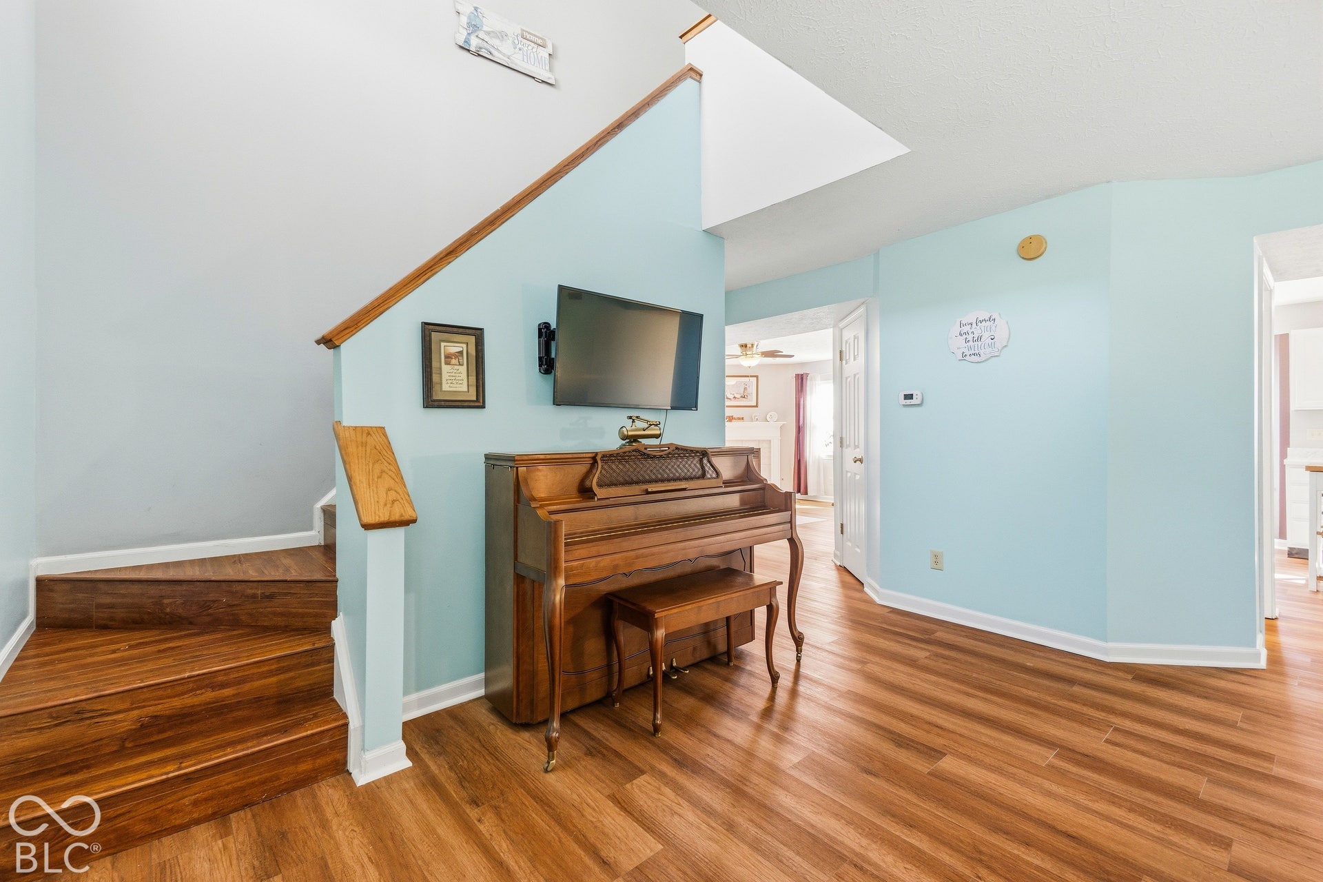 Wood-finish flooring throughout, two-story ceiling, and a prominent staircase with wood-finish treads and handrail