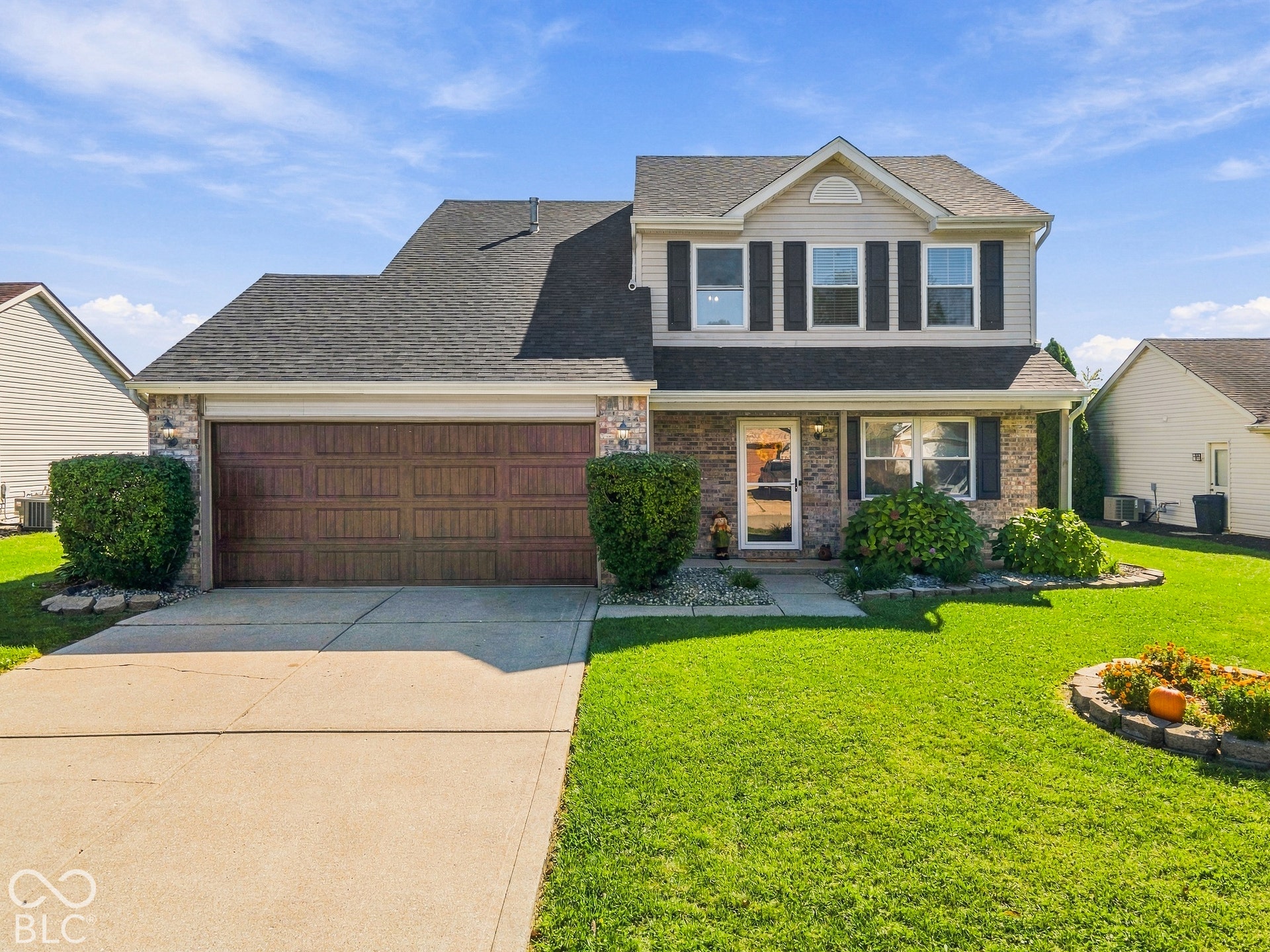 Two-story residence featuring brick and siding facade, an attached garage with a wood-finish door, and a concrete driveway