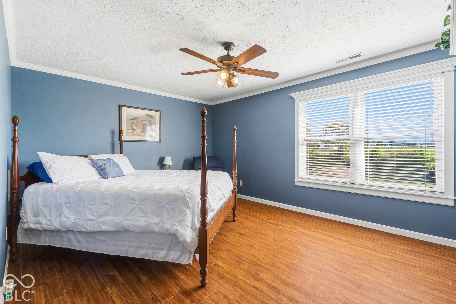 Wood-finish flooring, white window trim, and a ceiling fan with integrated lighting