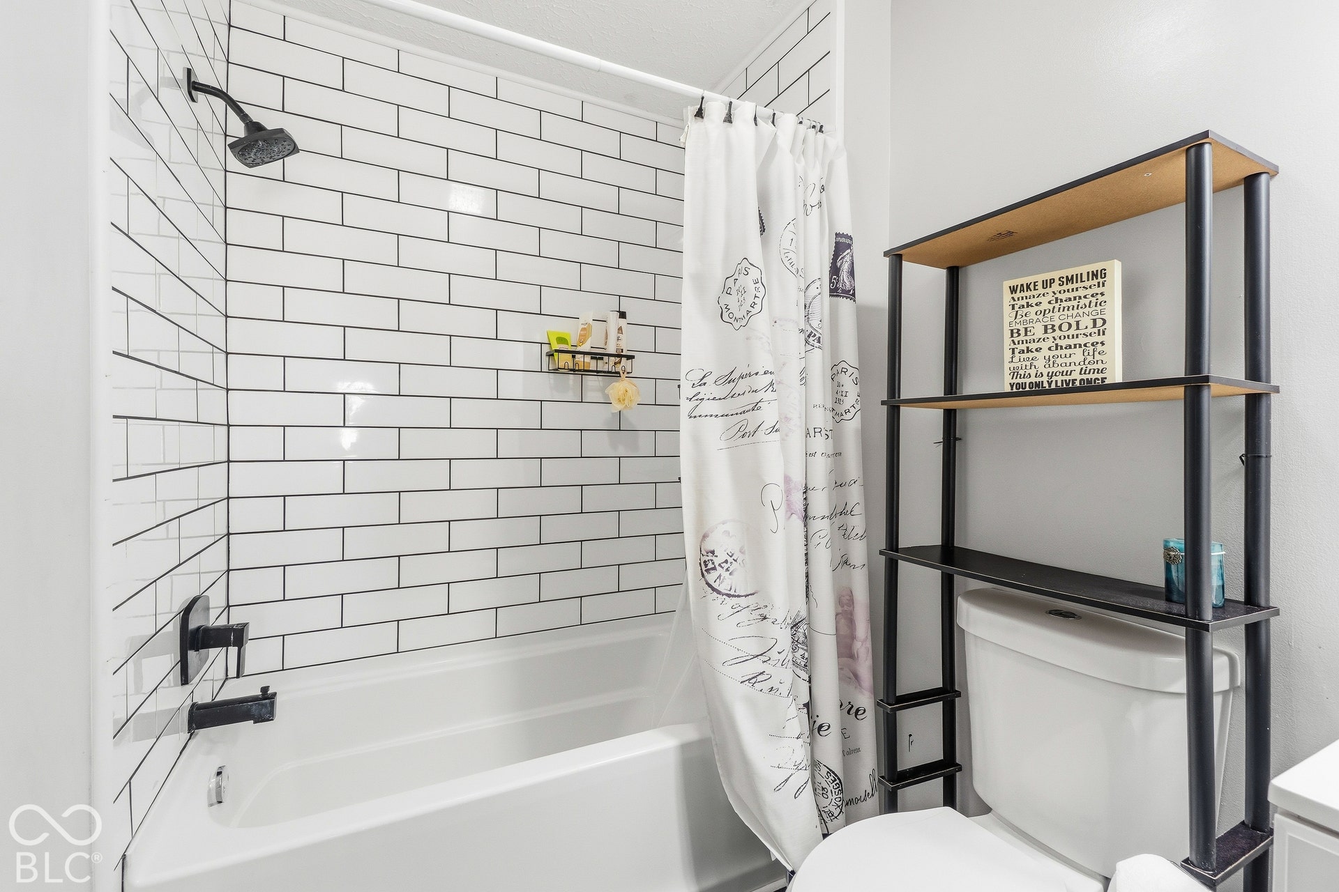 Subway tile shower surround with dark grout, white bathtub, and matte black shower fixtures