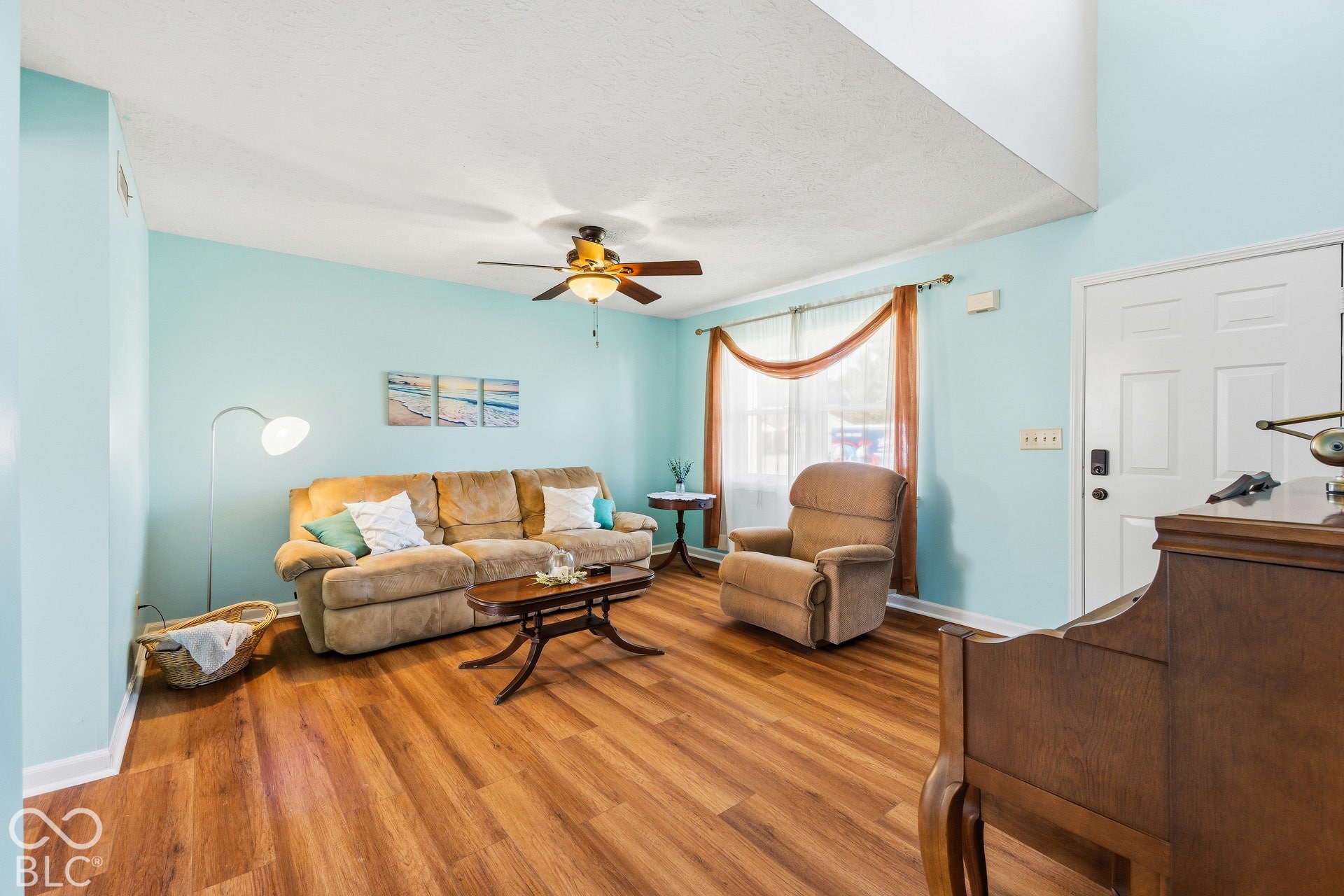 Wood-finish flooring throughout, ceiling fan with integrated lighting, and a prominent front entry door