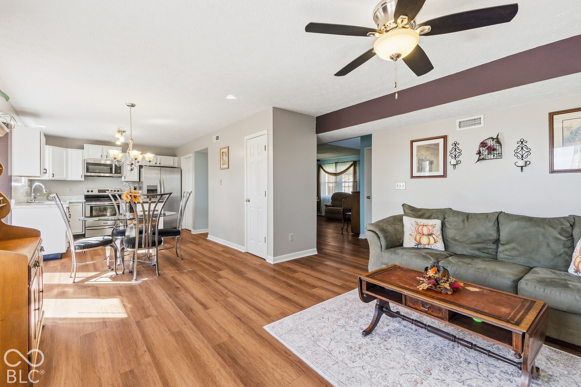 Open concept living area featuring wood-finish flooring, a ceiling fan with integrated lighting, and recessed kitchen lighting