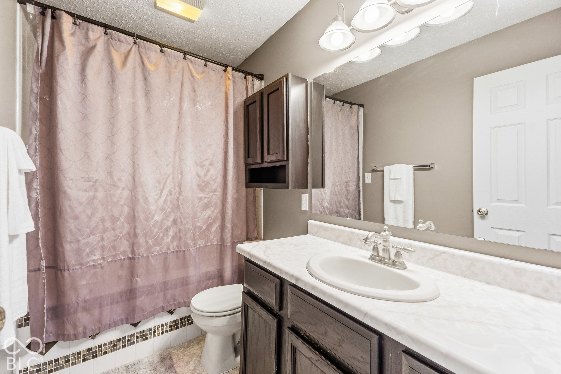 Bathroom featuring a vanity with a white countertop, an undermount sink, and dark wood-finish cabinetry