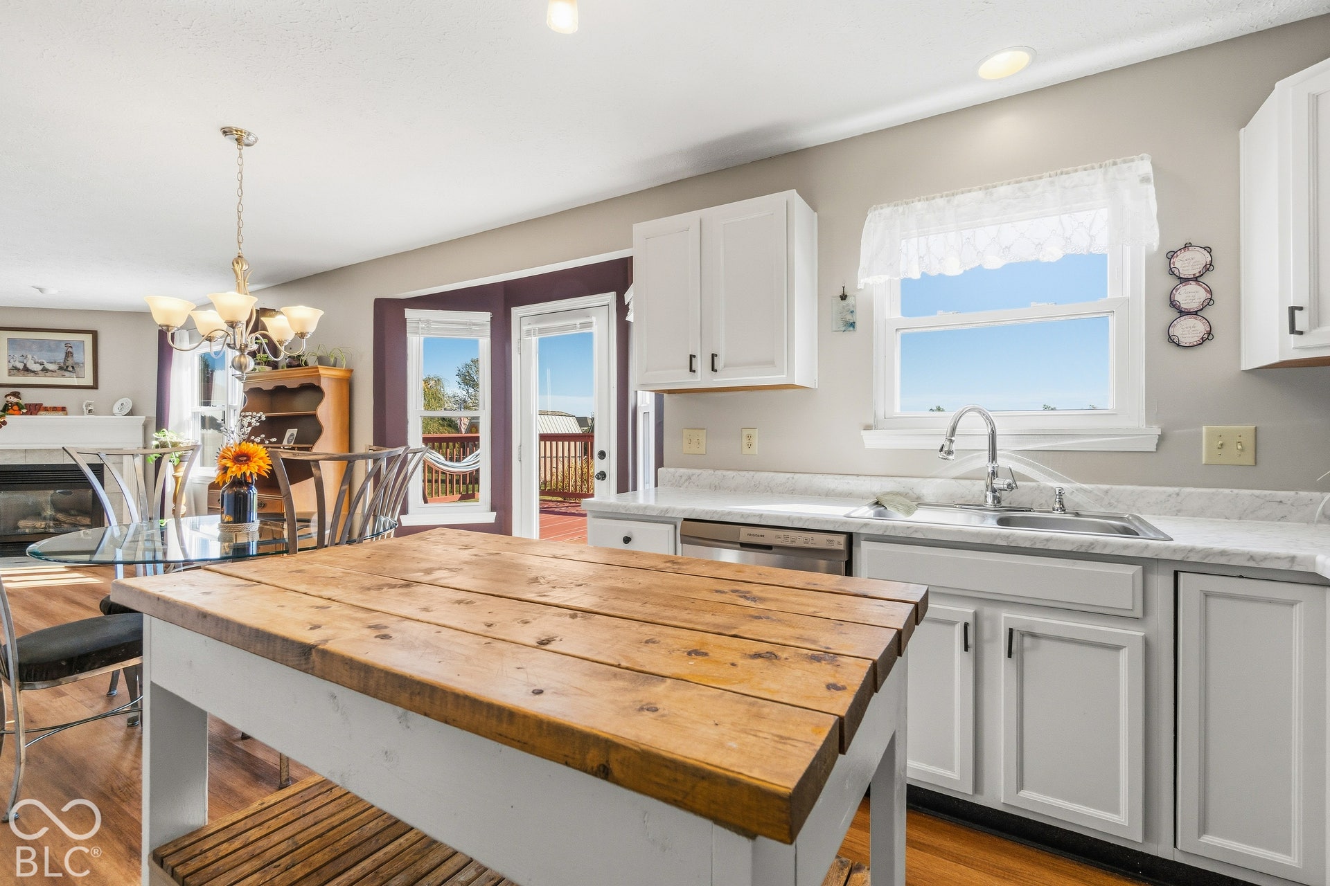 Kitchen with white cabinetry, stainless steel dishwasher, wood-finish flooring, and a countertop with an integrated sink