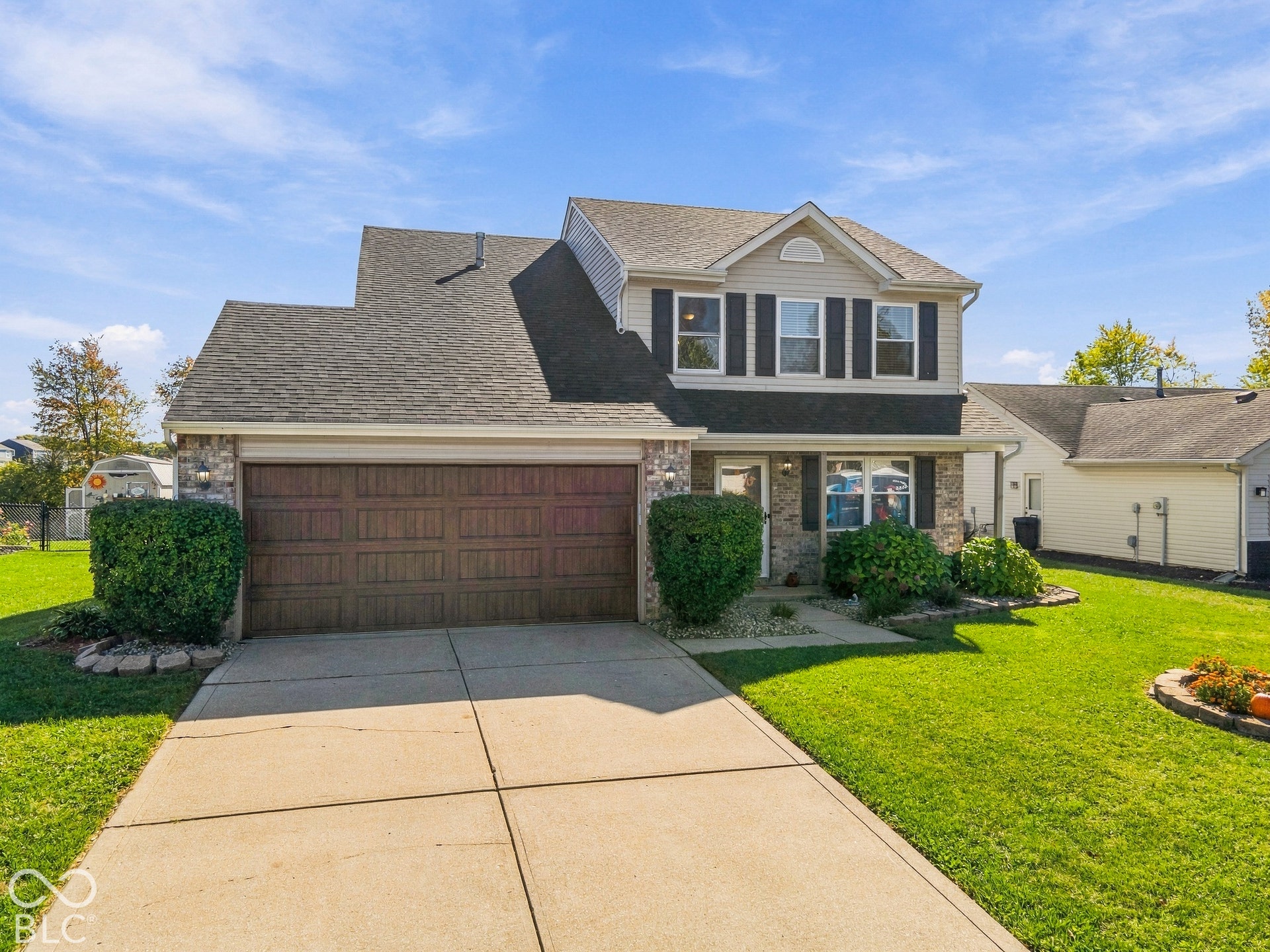 Two-story residence featuring a shingle roof and a two-car garage with a wood-finish door