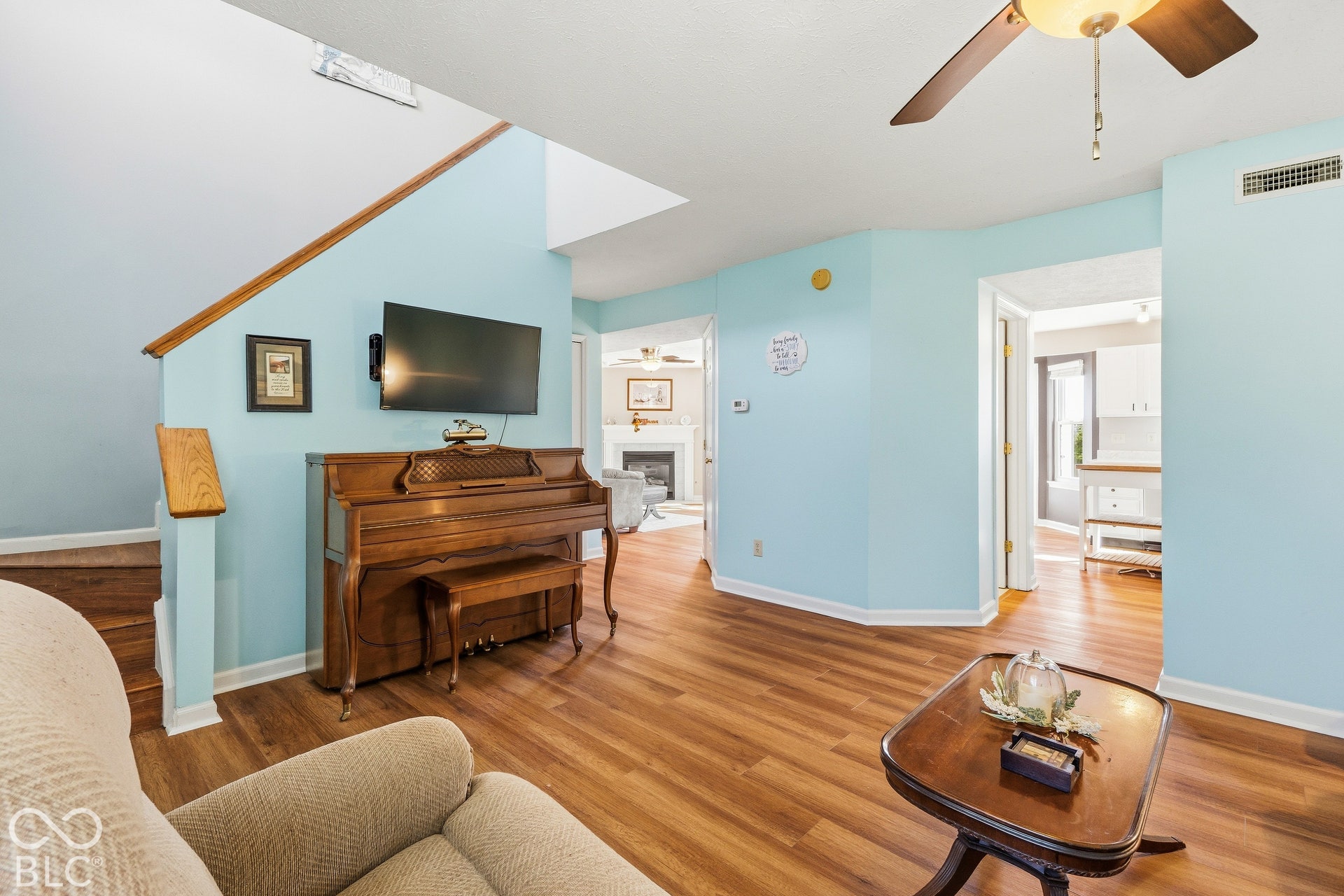 Wood-finish flooring, staircase with wood railing, recessed lighting, and ceiling fan with integrated light fixture