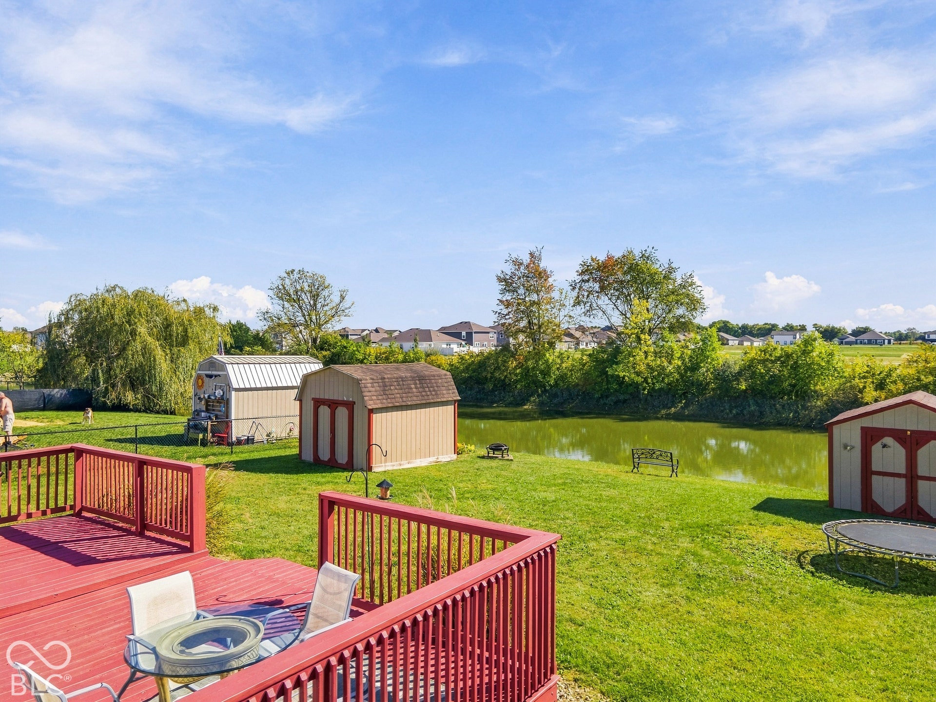 Expansive green lawn with a red-stained wooden deck and railings
