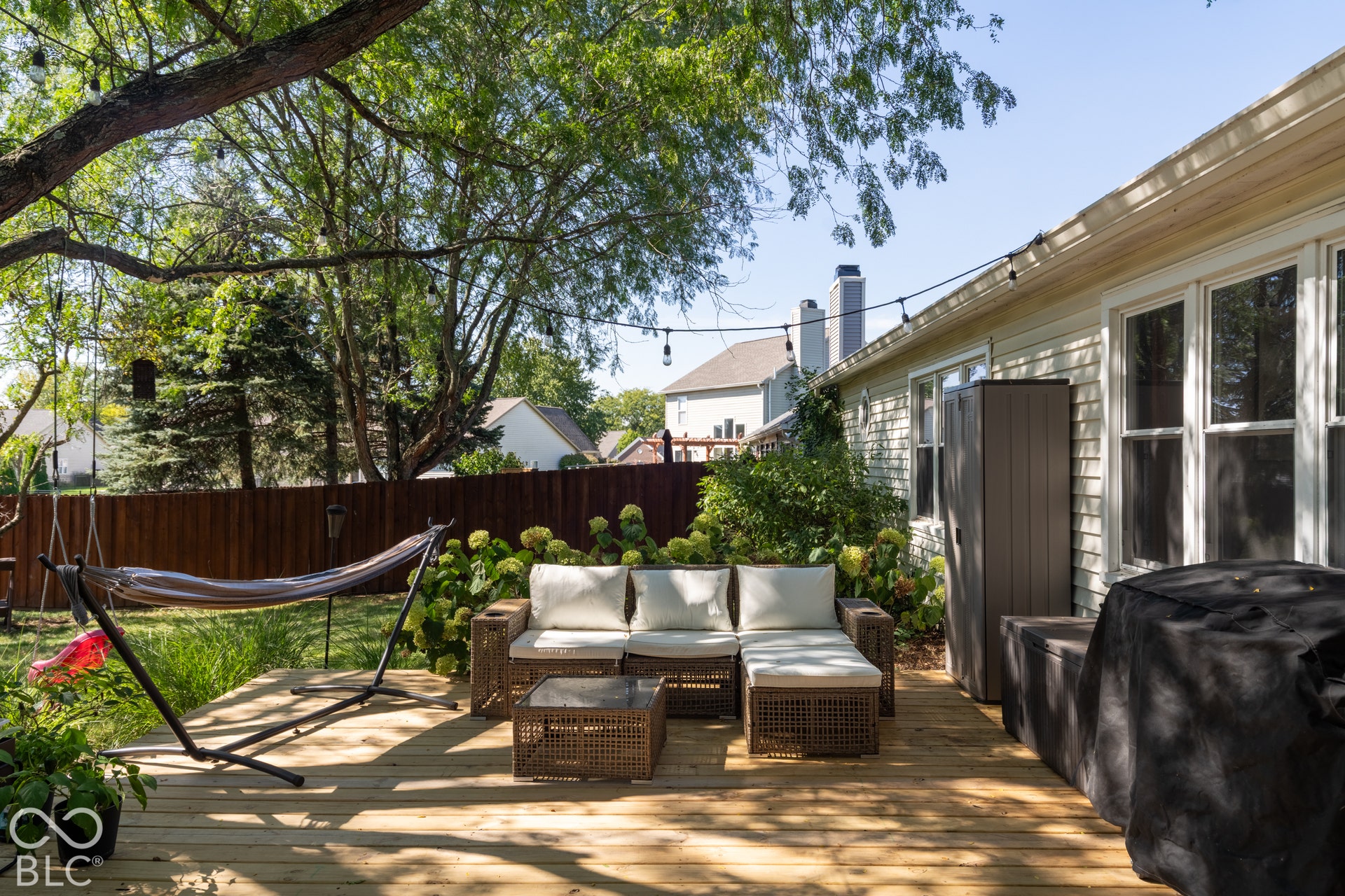 Expansive wooden deck with a privacy fence, mature trees, and a siding exterior