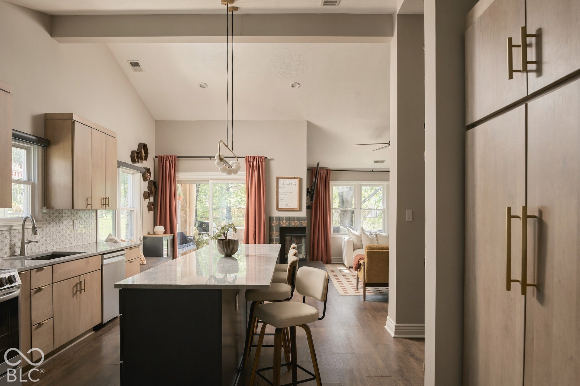 Vaulted ceiling with exposed beam, kitchen island with seating, stainless steel sink, wood-finish cabinetry, and dark wood-finish flooring
