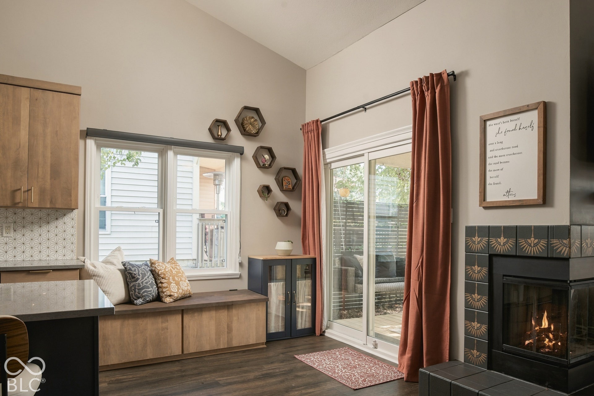 Vaulted ceiling, built-in window bench, sliding glass door, tiled fireplace surround, and wood-finish flooring
