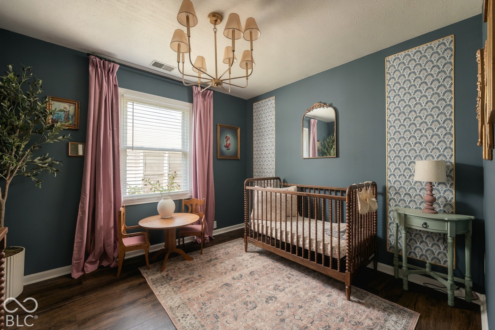 Wood-finish flooring with baseboard trim, a window with blinds and curtains, and a gold-toned chandelier