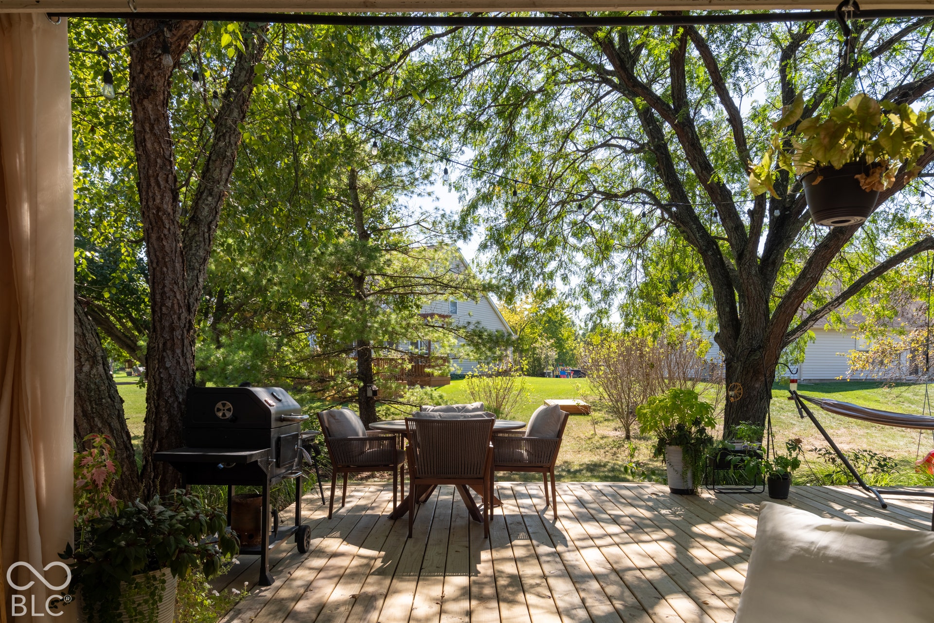 Spacious wood deck with surrounding mature trees and string lighting