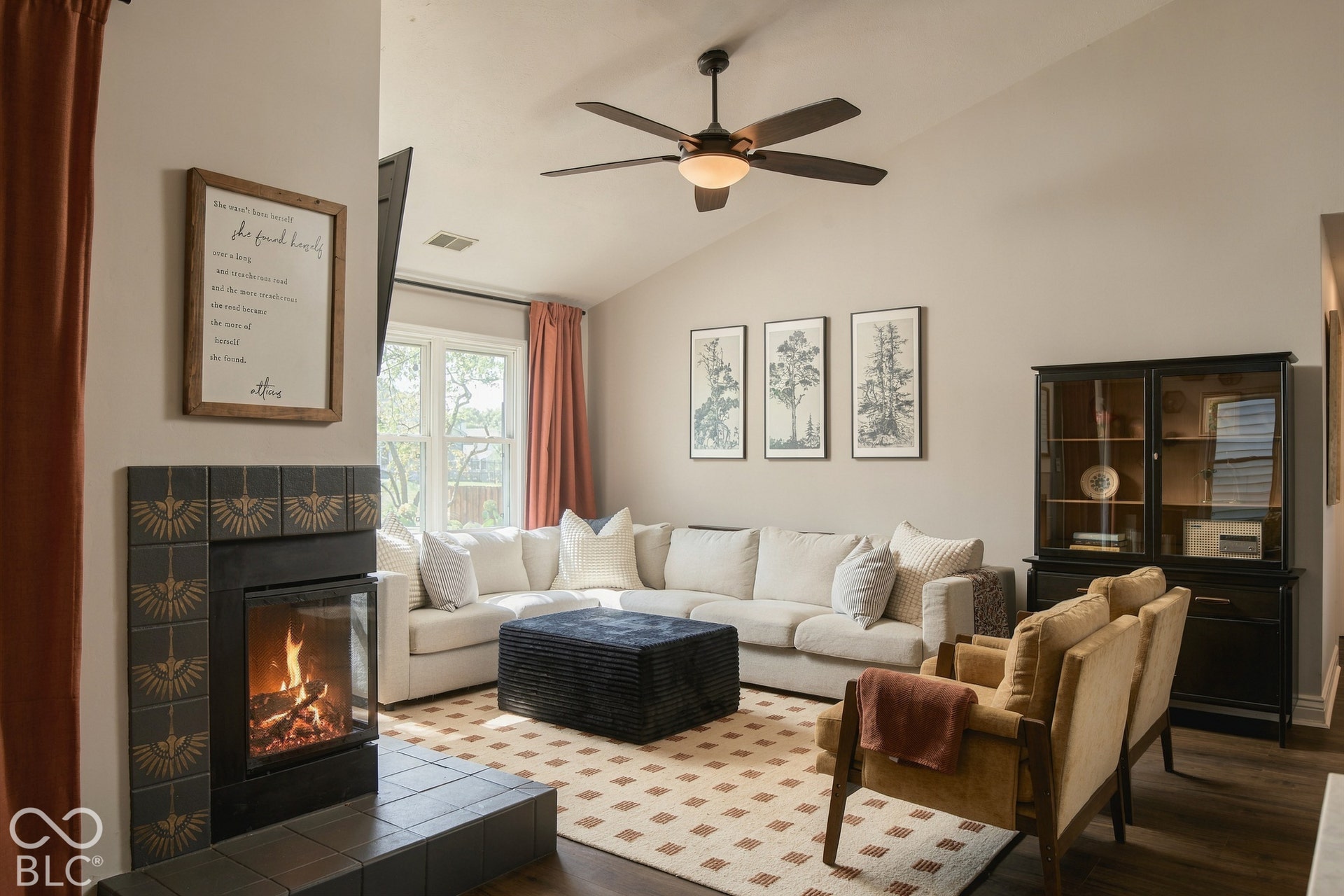 Vaulted ceiling with a ceiling fan, fireplace with a tile surround, wood-finish flooring, and window with natural light