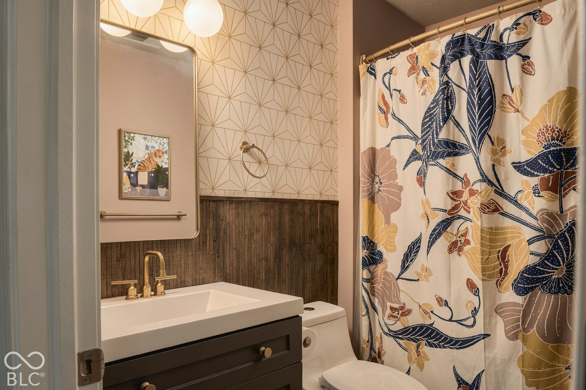 Vanity with a white integrated sink, brass-finish faucet, and dark wood-finish cabinetry