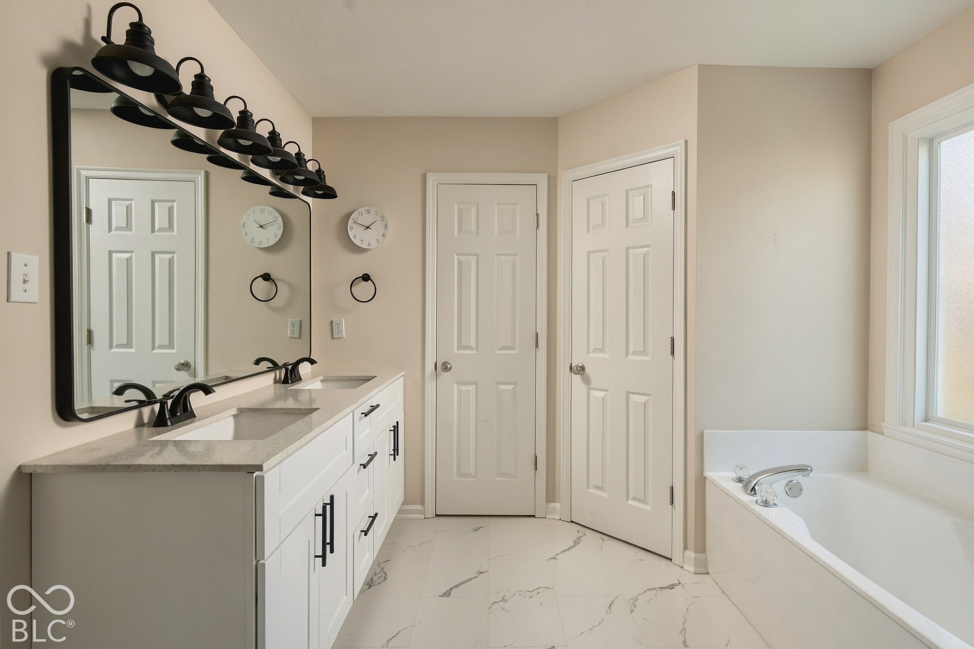 Double vanity with white cabinetry, matte black hardware, and light-toned countertops