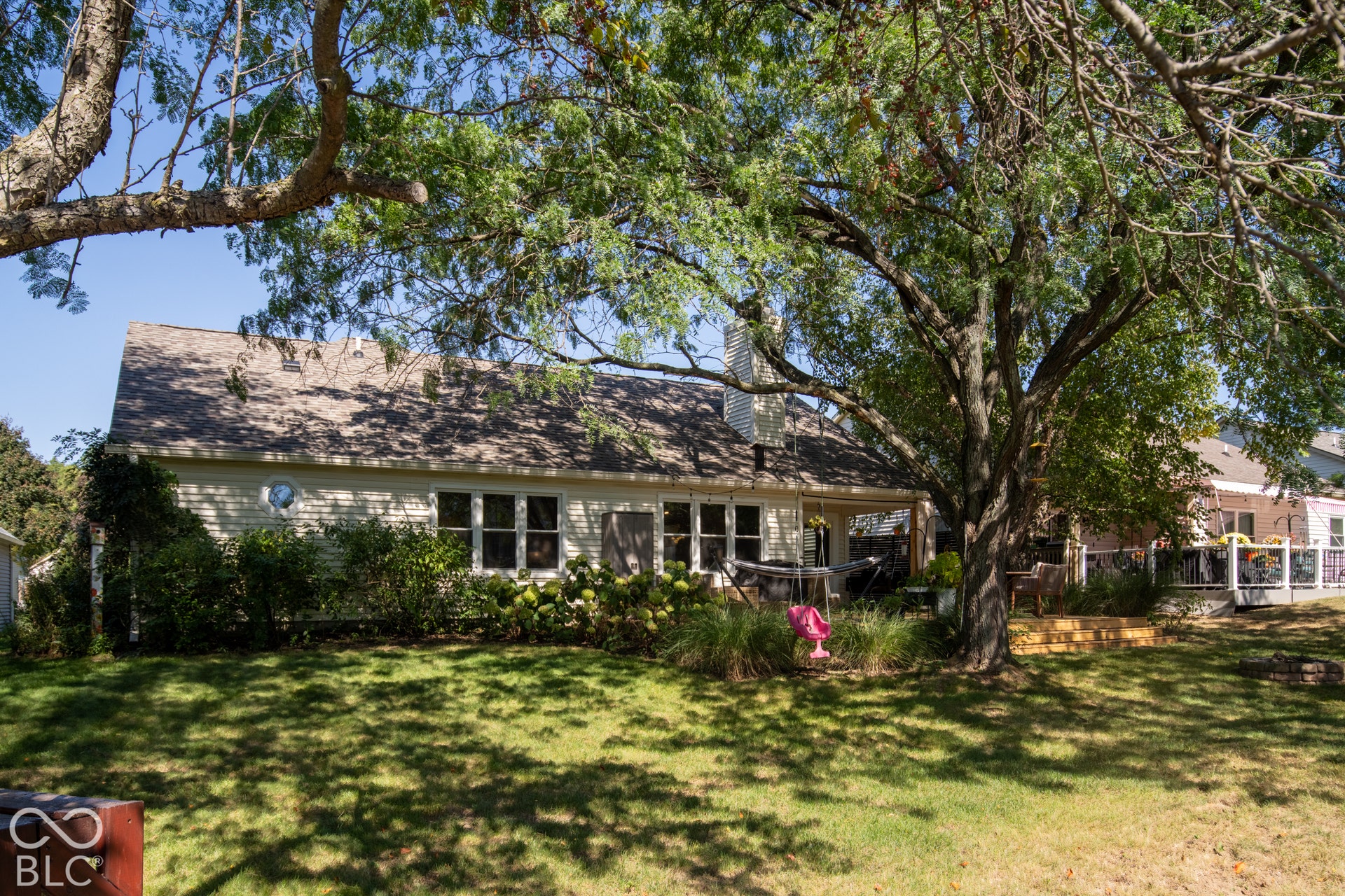 Expansive backyard with a manicured lawn, mature trees, and established perimeter landscaping