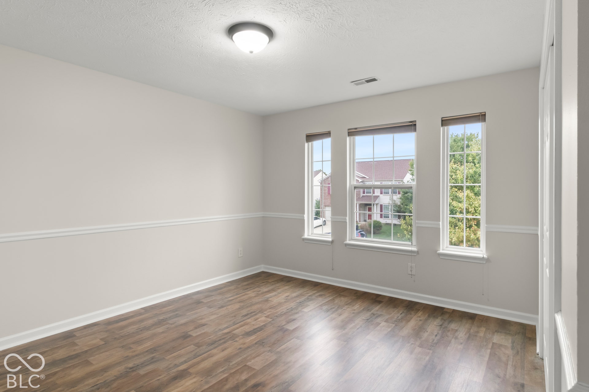 Light-toned walls with chair rail molding, wood-finish flooring, and multiple windows providing natural light