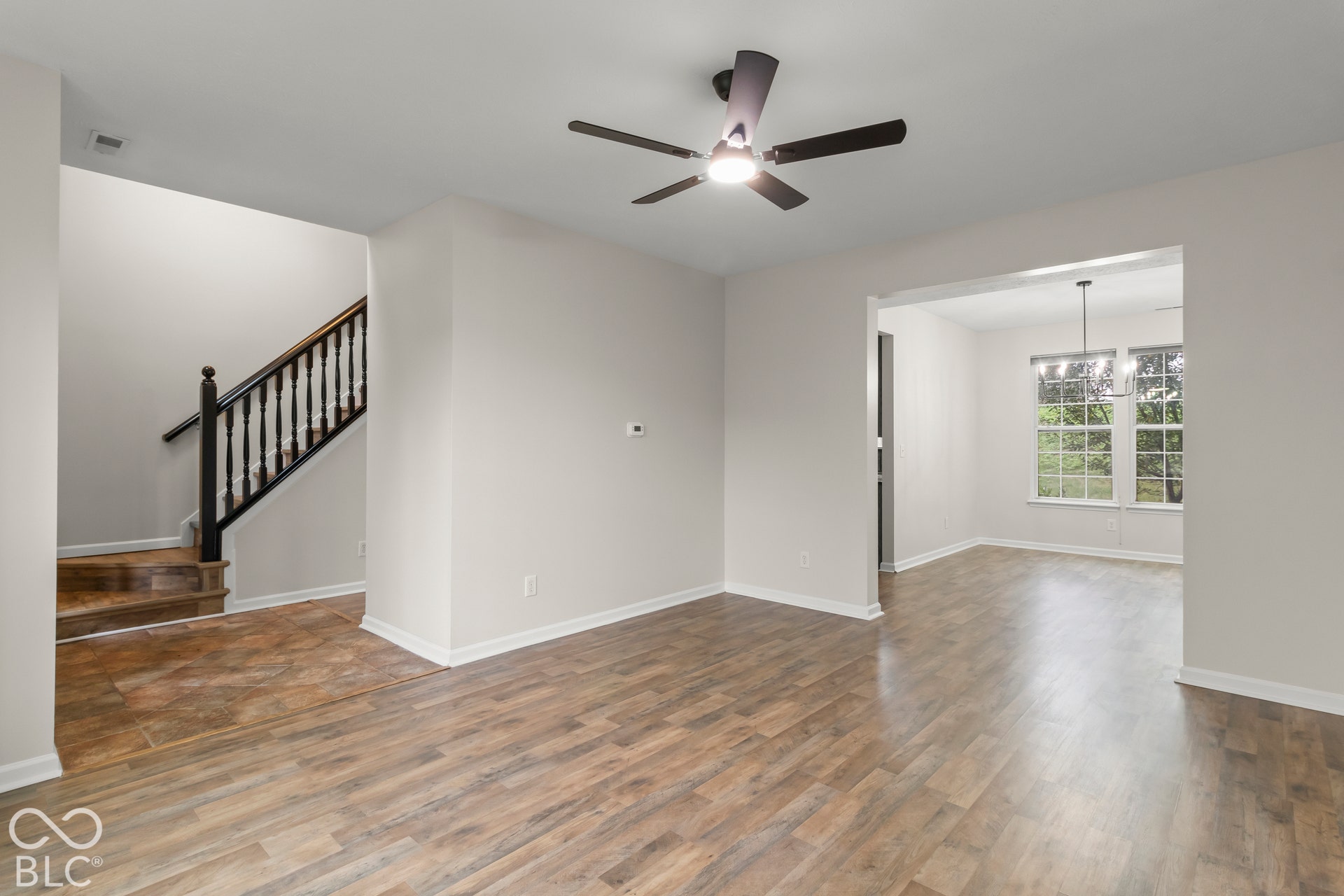 Wood-finish flooring throughout, with a contrasting staircase featuring dark wood newel posts and balusters